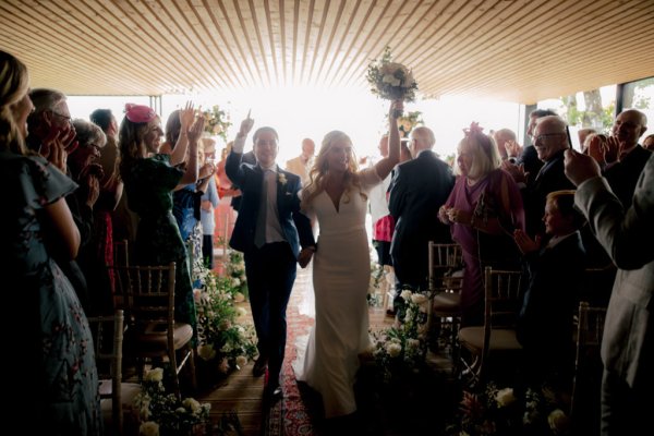 Bride and groom exit ceremony guests are clapping