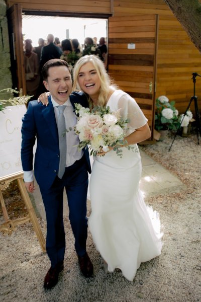 Bride and groom are laughing bride is holding flowers