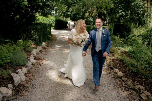 Bride and groom walk through garden