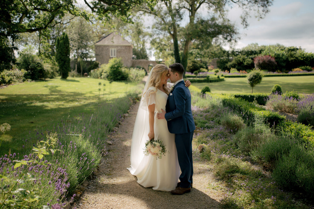 Bride and groom embrace in garden