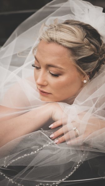 Bride in wedding car covered with veil