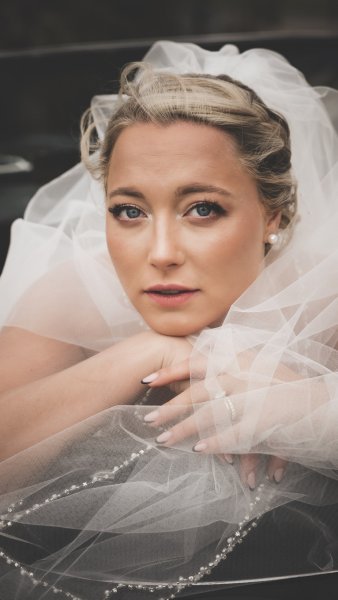 Bride in wedding car covered with veil