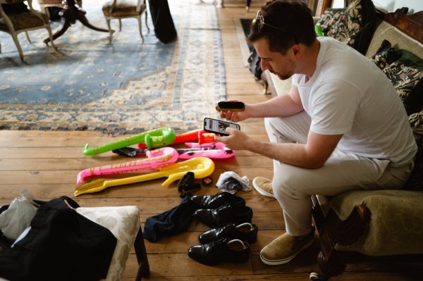 Groom holding phone wedding shoes on ground