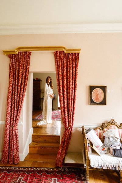 Bride getting ready in room curtains