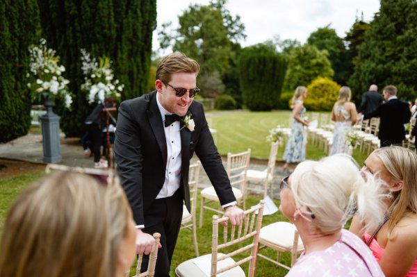 Man wearing sunglasses in audience talking to guests