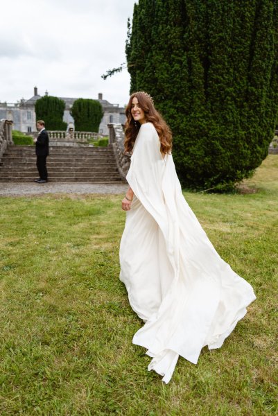 Bride on her own standing on grass over the shoulder