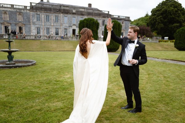 Bride and groom high-five outside on grass