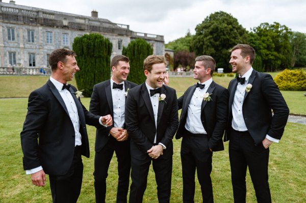 Groom and groomsmen laugh celebrate