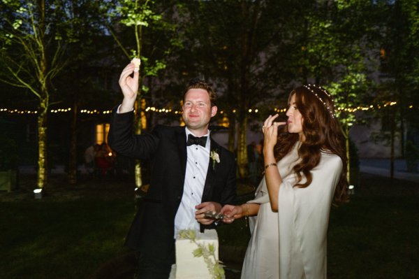 Dark photo of bride and groom eating wedding cake cutting