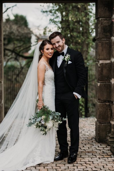 Bride and groom smile in courtyard