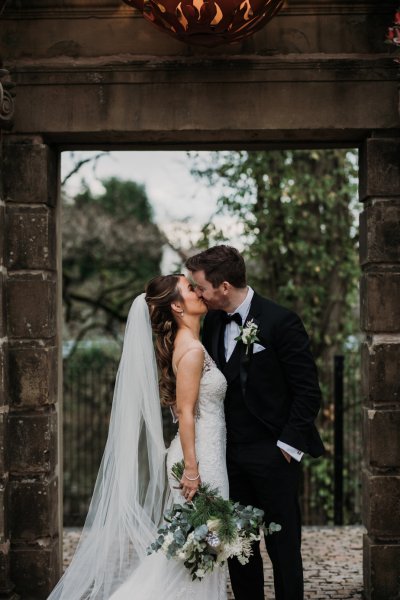 Bride and groom kiss in courtyard