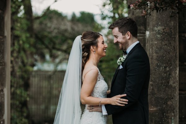 Exterior bride and groom in courtyard forest setting looking at each other