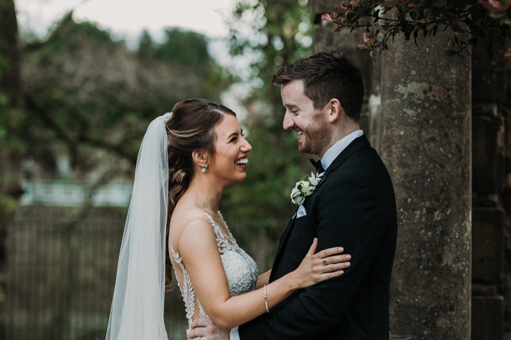 Exterior bride and groom in courtyard forest setting looking at each other