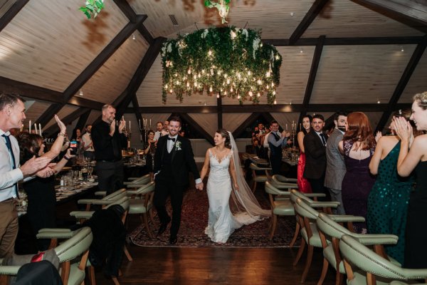 Bride and groom enter dining room with guests clapping