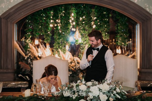 Bride and groom laugh during ceremony at table speech speeches