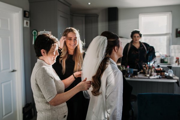 Veil on bride's head hairstylist laughing