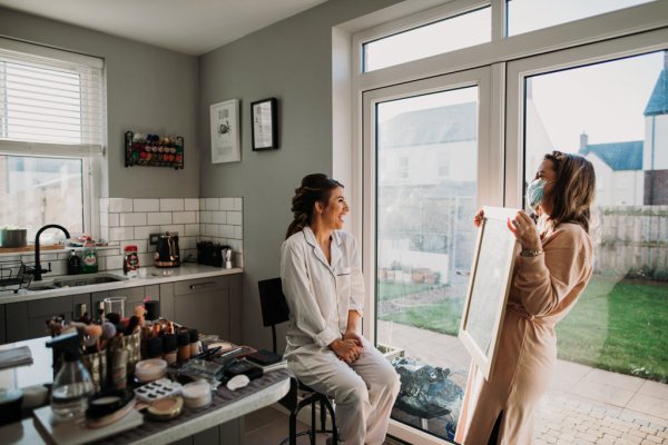 Bride inside before wedding getting ready looking at hair in mirror