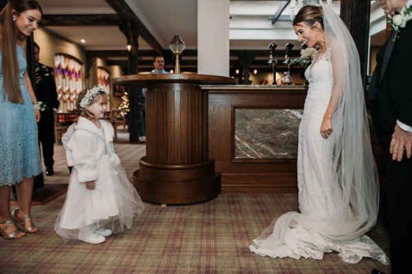 Bride approaches little girl wearing white