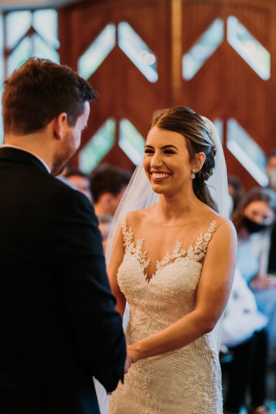 Bride and groom exchanging wedding bands/rings smiling