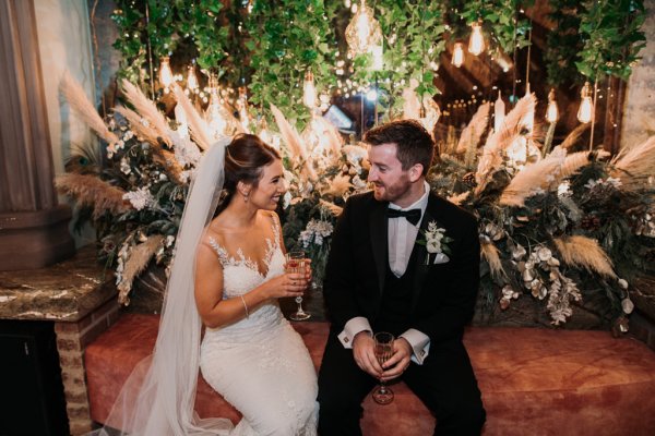 Bride and groom looking at each other holding wine glasses/champagne