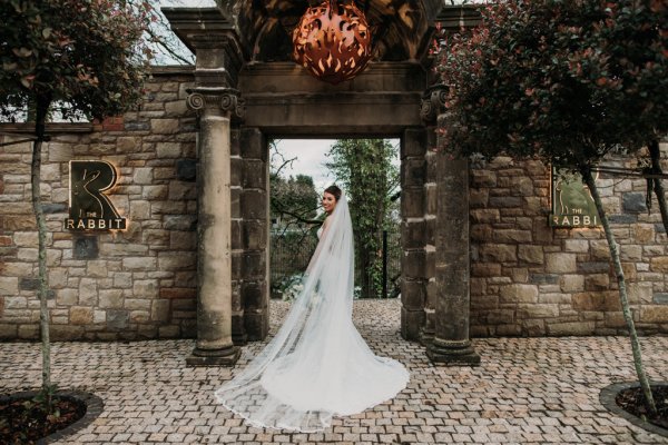 Exterior shot of bride long train and veil flowers forest detail