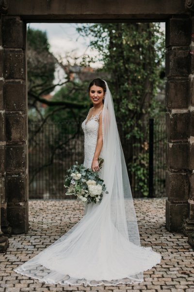 Exterior shot of bride long train and veil flowers forest detail