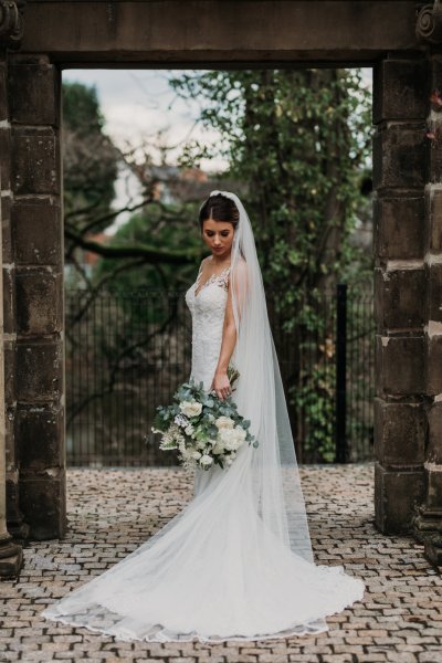 Exterior shot of bride long train and veil flowers forest detail