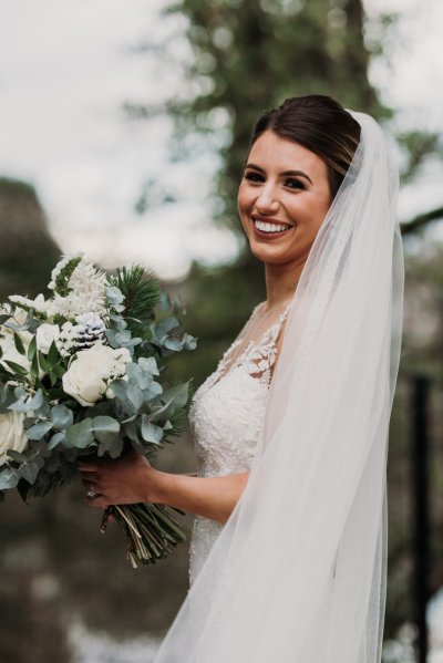 Exterior shot of bride long train and veil flowers forest detail