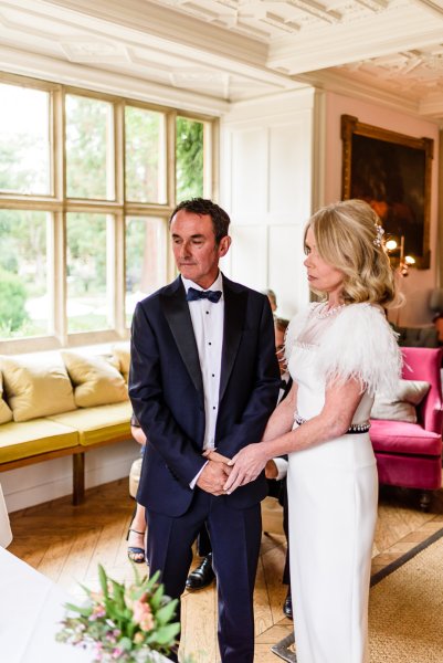 Bride and groom at alter with guests holding hands