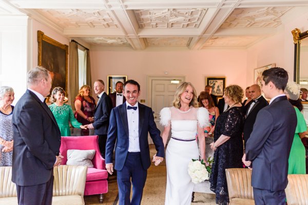 Bride and groom exit ceremonial room with guests