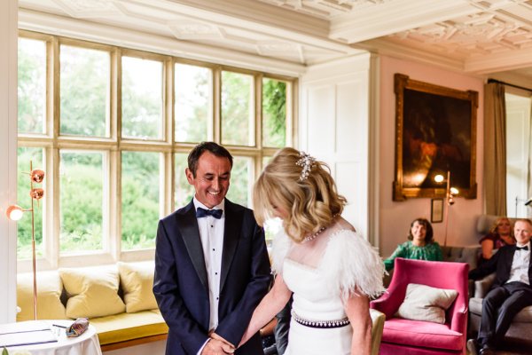 Bride and groom in front of guests at alter laughing