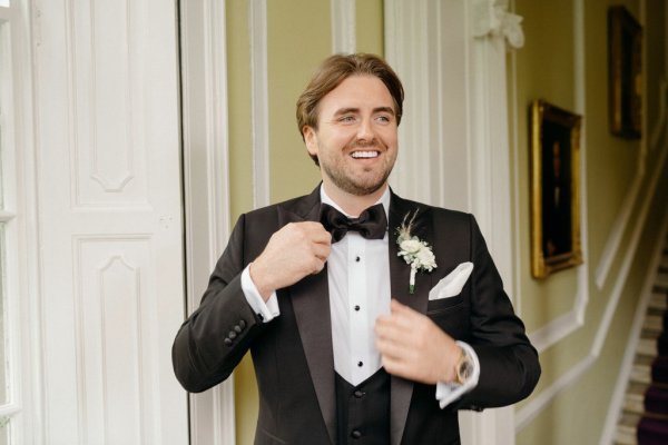 Image of groom fixing suit jacket tuxedo suit and tie