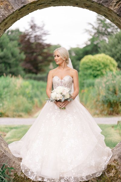 Bride stands in oval-shaped archway garden