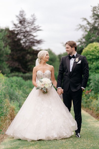 Bride and groom walk in garden