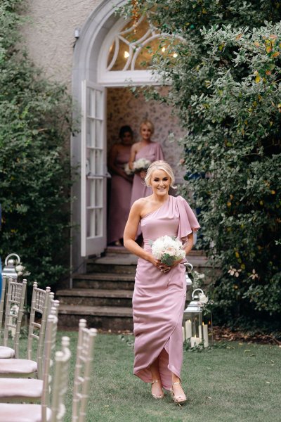 Bridesmaid walks down the aisle holding bouquet of flowers