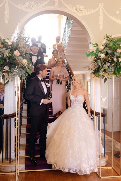 Bride and groom bridesmaids in background standing on staircase