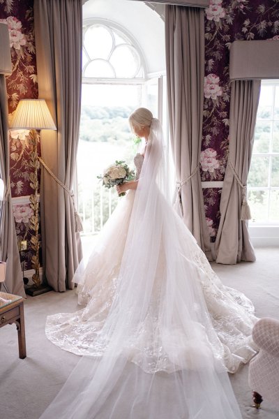 bridal gown/dress detail bride looking down at flowers at window