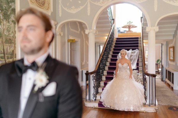 Bride behind groom unfocused at stairs