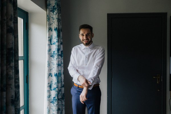 Groom getting ready putting on suit and tie white shirt