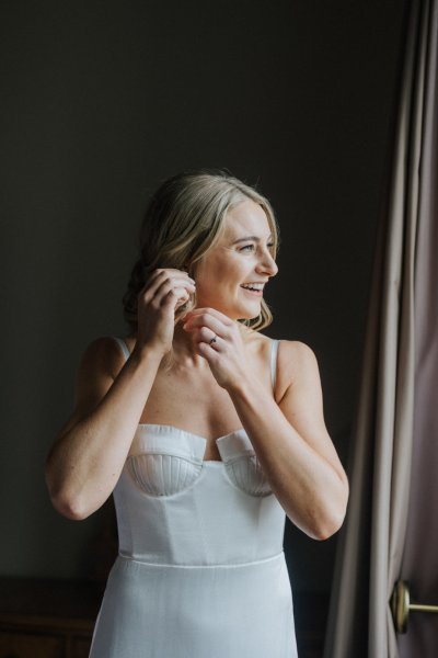 Bride putting on earrings