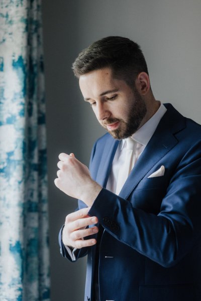 Groom getting ready putting on suit and tie