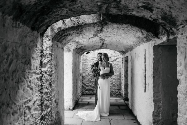 Bride and groom under arch with sunflowers black and white