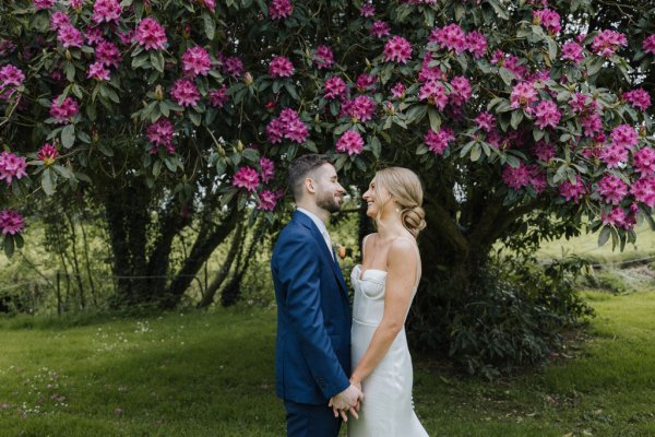 Bride and groom under flower bush in garden/forest