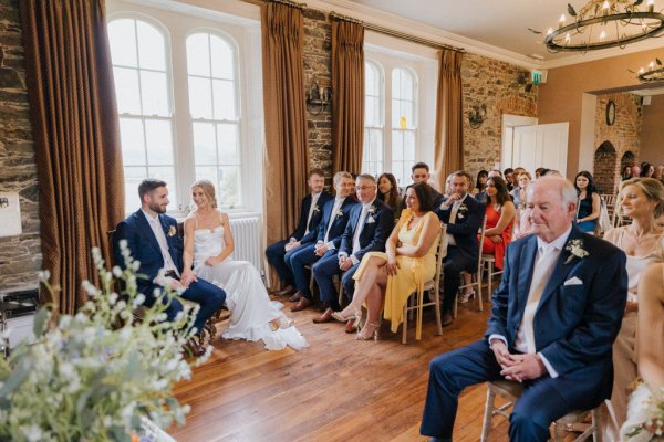 Ceremonial room bride and groom seated with guests in background