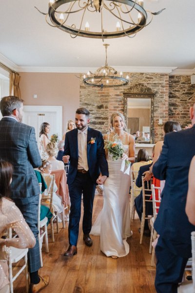 Bride and groom exit ceremony guests clapping