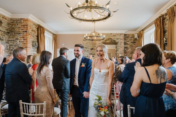 Bride and groom exit ceremony guests clapping