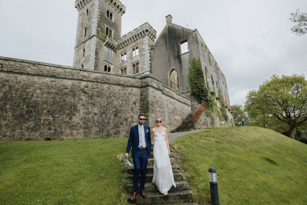 Bride and groom standing on grass exterior garden/forest trees walking down steps