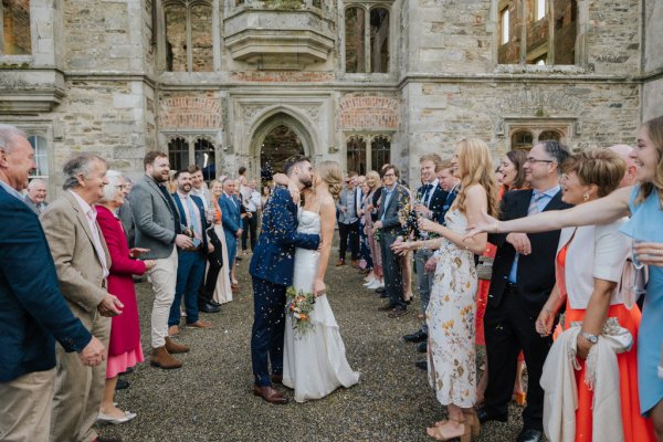 Bride and groom exterior church with guests clapping kissing kiss