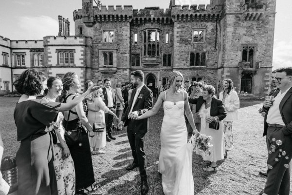 Bride and groom exterior church with guests clapping black and white