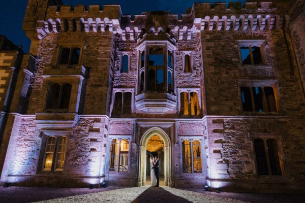 Evening dark exterior shot of wedding venue with couple under archway